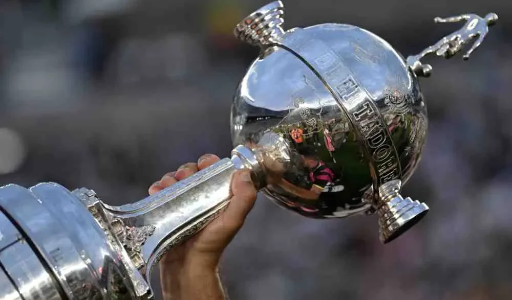 Persona sosteniendo en alto el trofeo de la Copa Libertadores de América.