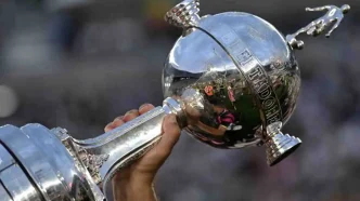 Persona sosteniendo en alto el trofeo de la Copa Libertadores de América.