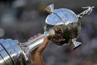 Persona sosteniendo en alto el trofeo de la Copa Libertadores de América.