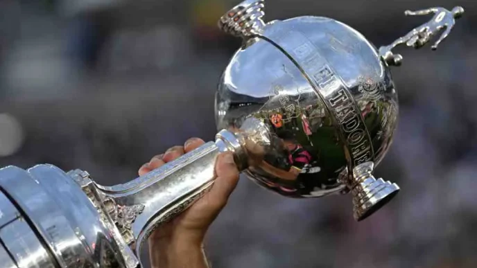 Persona sosteniendo en alto el trofeo de la Copa Libertadores de América.